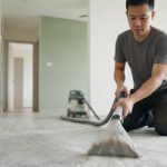 Professional technician using deep hot water extraction to clean cement dust and drywall powder from carpet in a Singapore BTO flat.