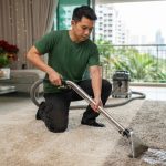 Professional carpet cleaning technician using hot water extraction and fabric protection on a matted living room rug in Singapore before festive gatherings.